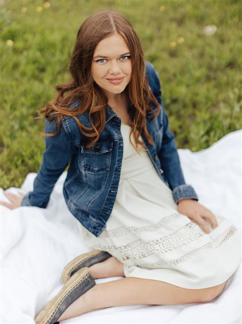 A teenage girl in a white dress and a blue jean jacket
